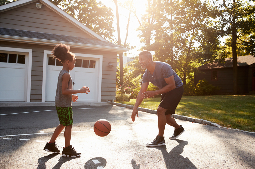 Man playing basketball with young daughter