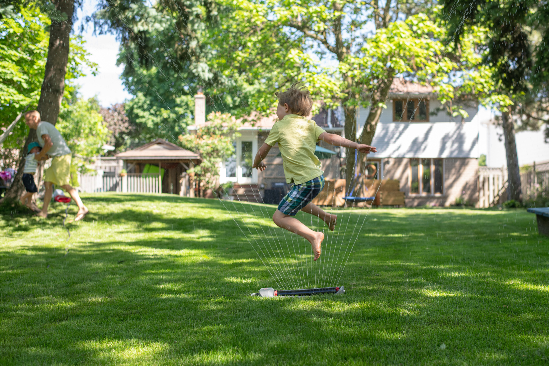 Young child jumping through sprinkler